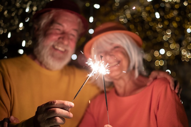 Foto un uomo e una donna anziani sfocati festeggiano l'evento del nuovo anno facendo una festa di notte con le luci scintillanti