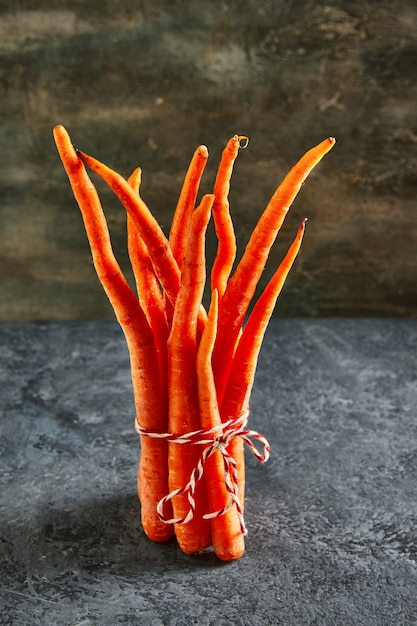 Deformed organic carrots on a rope on a blue background