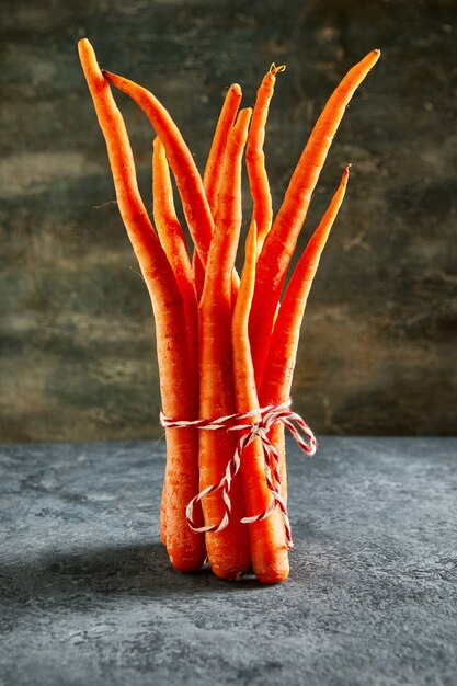 Deformed organic carrots on a rope on a blue background