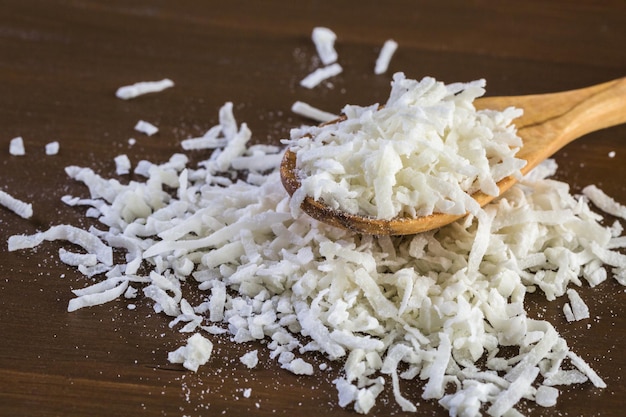 Dehydrated coconut flakes on a wood background.