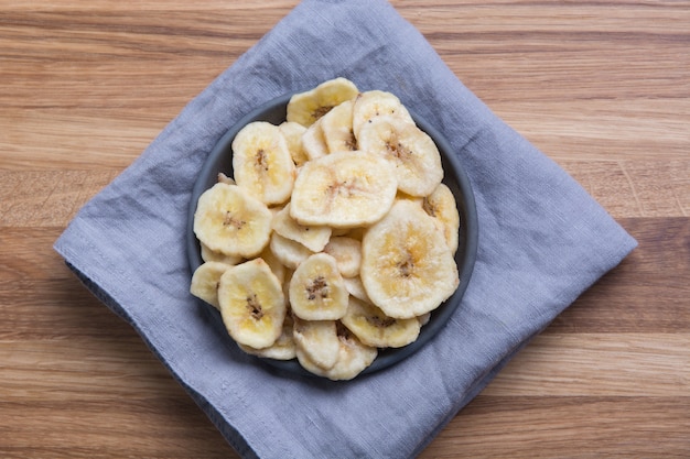 Dehydrated, dried banana chips on wooden board. View from above.