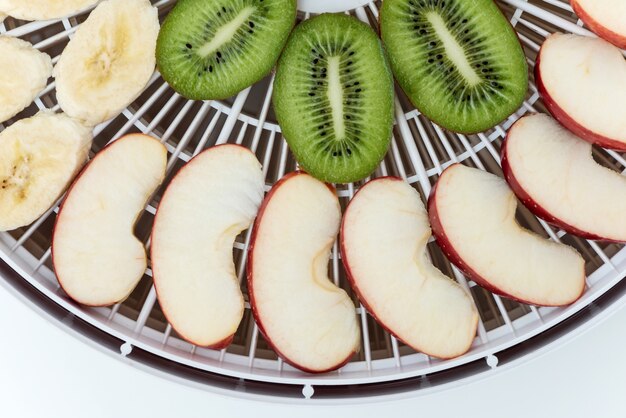 Dehydrator tray with slices of kiwi and apples. Top view.