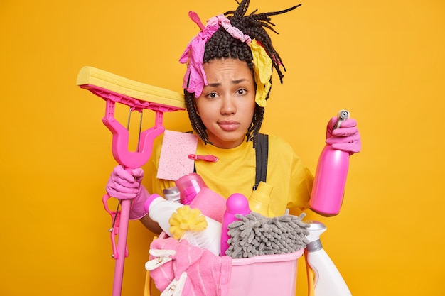 Dejected unhappy housemaid has braids busy cleaning the house