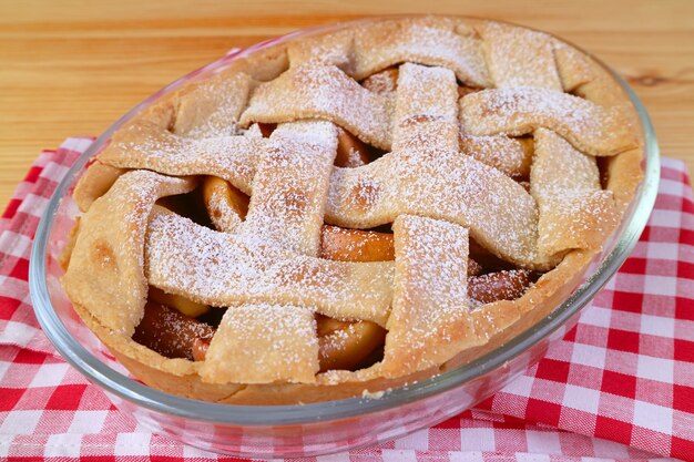 Восхитительный свежеиспеченный домашний вкусный и полезный яблочный пирог на кухонной ткани в клетку