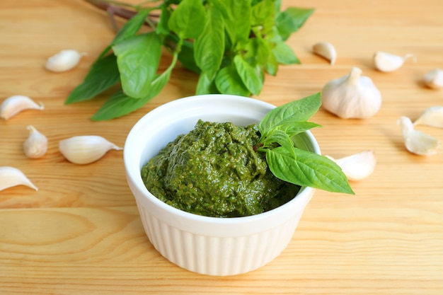 Delectable Homemade Fresh Basil Pesto Sauce in White Bowl with It's Ingredients in the Backdrop