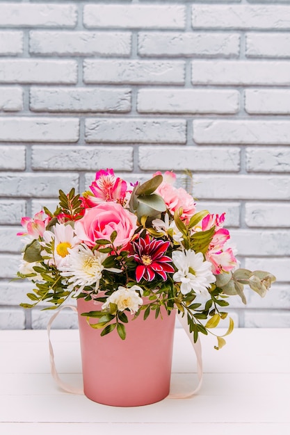 Delicaat boeket van verschillende bloemen in roze verpakking.