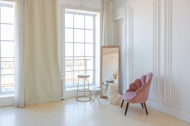사진 대낮에 치장 벽토 몰딩이 있는 흰색 벽과 파스텔 핑크 색상의 현대적인 세련된 가구가 있는 섬세하고 아늑한 조명 인테리어