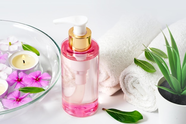 Delicate background intimate hygiene gel white towels and a container with pink flowers for aromathe...