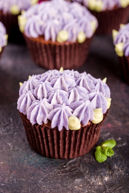 Delicate and beautiful chocolate cupcakes with cream, mint, cinnamon sticks, tea on the table.