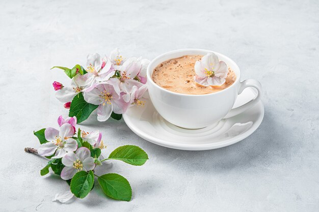Фото капучино в цветах Premium Photo Delicate, beautiful flowers and a cup of cappuccino on a light gra