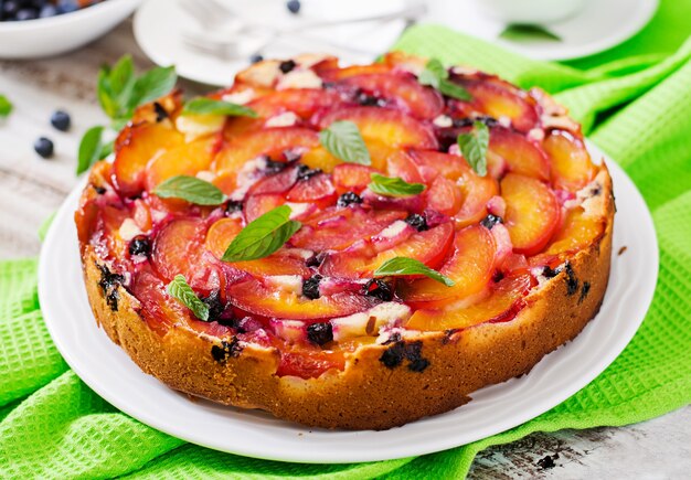 Фото Нежный бисквитный пирог с персиками и черникой.