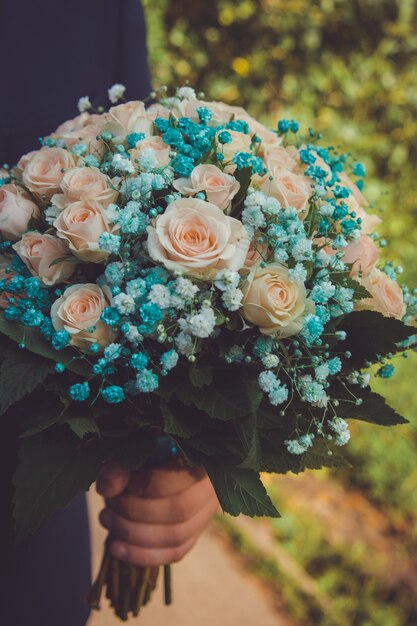 Delicate bouquet of cream pastel roses in the hands of the groom close-up