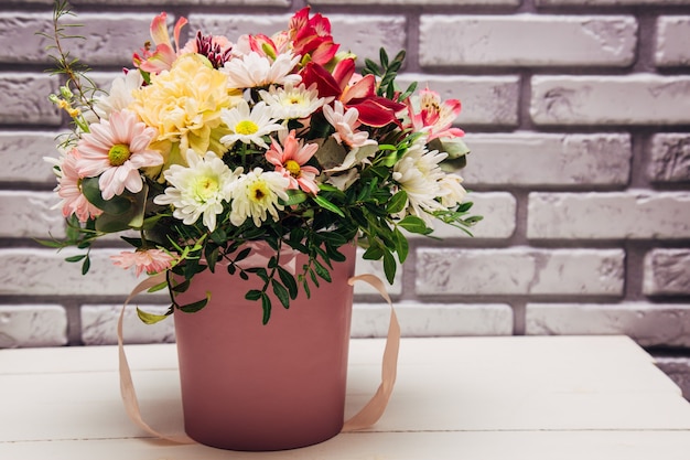 Delicate bouquet of different flowers in pink packaging. 