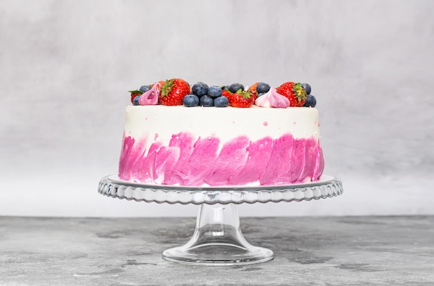 Delicate cake garnished with fresh strawberries blueberries on a gray plain background Festive dessert