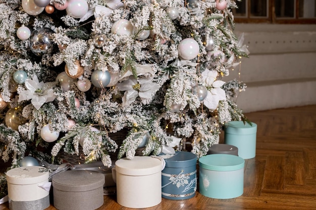 Нежные елочные подарки в светлой комнате в скандинавском стиле на Рождество или Новый год праздничные подарки в сине-розовой порошковой упаковке возле елки