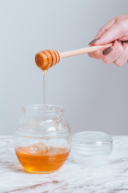 Delicate female hand with honey pot