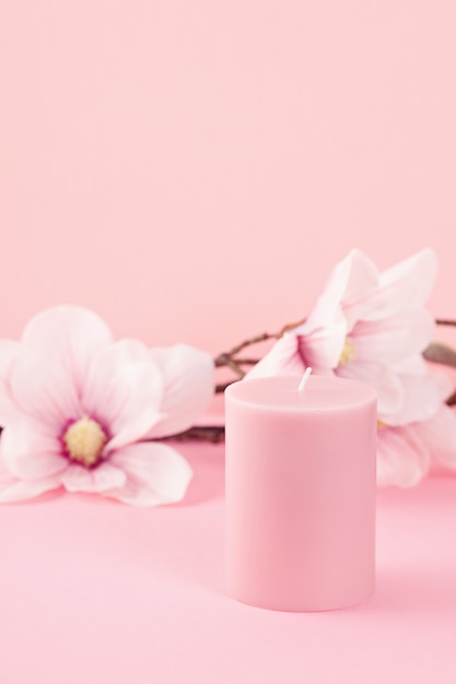 Delicate flower scented candle over pink wall