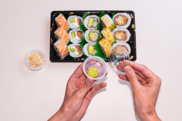 Delicate hands opening wasabi to eat with sushi healthy food