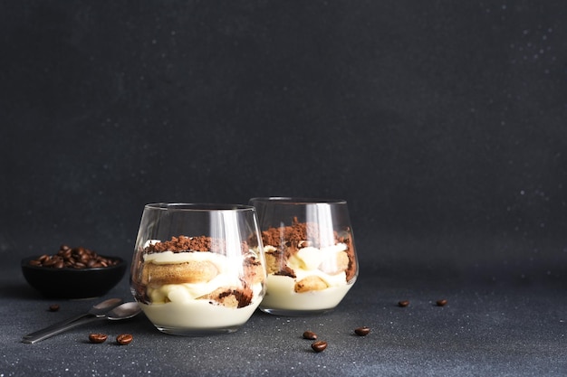 Delicate Italian dessertTiramisu with coffee in a glass on a black background