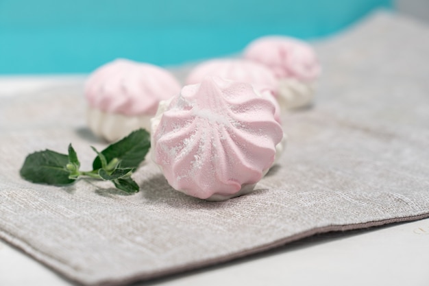 Delicate light marshmallows with a mint leaf on a light