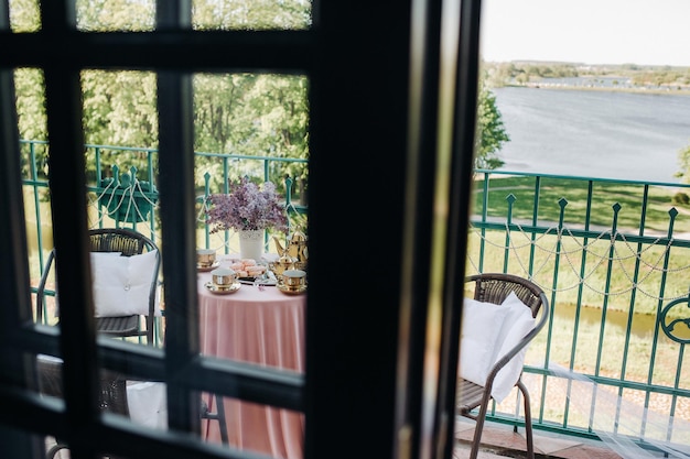 Delicate morning tea table setting with lilac flowers in Nesvizh castle antique spoons and dishes on the table with a pink tablecloth