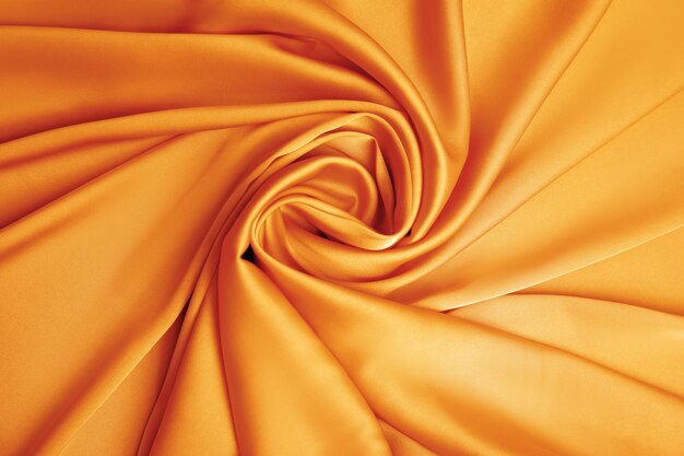 Delicate orange silk fabric as background top view