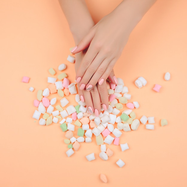 Delicate pink manicure on a trendy coral table.