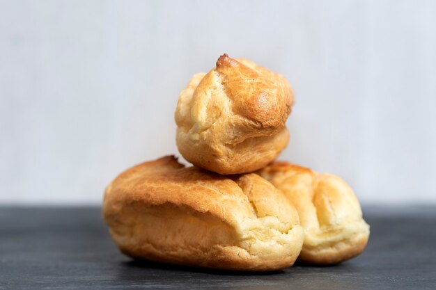 Delicate profiteroles or eclairs without cream. Close up. White background.