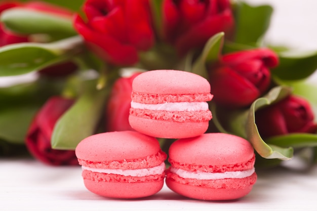 Foto tulipani e macarons rossi delicati su di legno. avvicinamento. composizione di fiori. primavera floreale. san valentino, pasqua, festa della mamma.