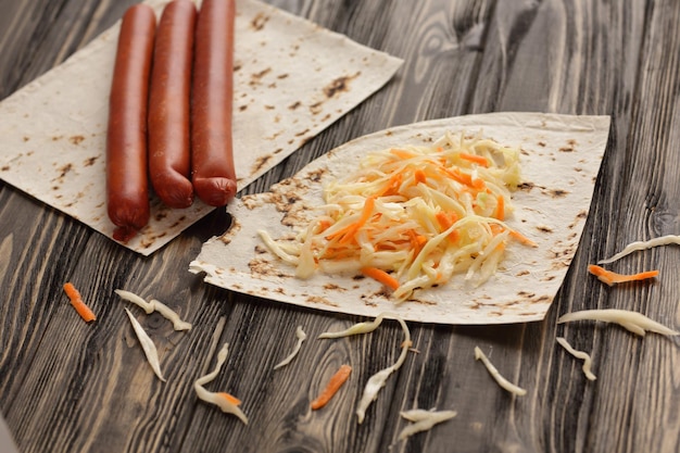 Delicate sausages cabbage and pita bread on wooden background