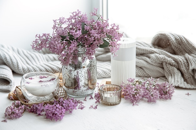 Delicate spring arrangement with flowers in a vase, a glass of milk and home decor details.