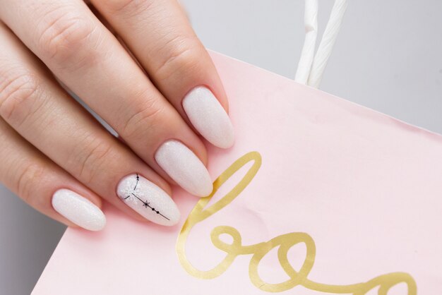 Delicate vrouwen manicure op een lichte papieren zak.