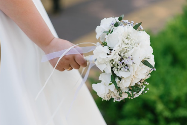 Delicate wedding bouquet with white hydrangea in the hands of the bride