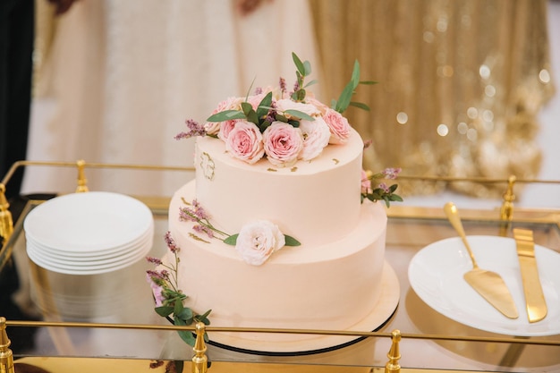 Delicate wedding cake decorated with flowers on a trolley