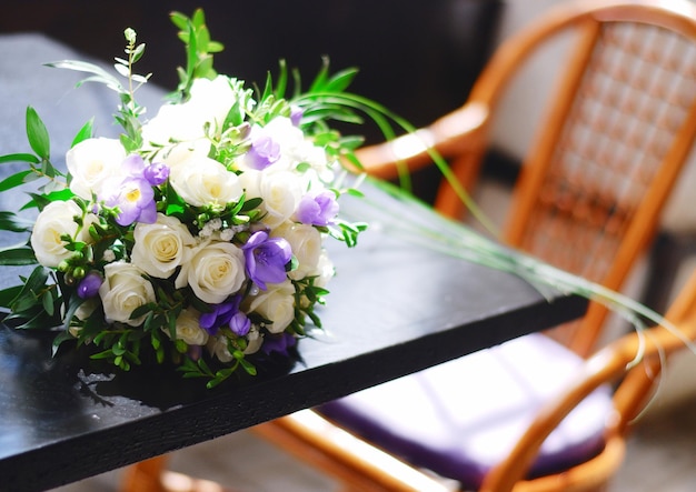 カフェのテーブルの上の花嫁の繊細な結婚式の白と紫のブーケ