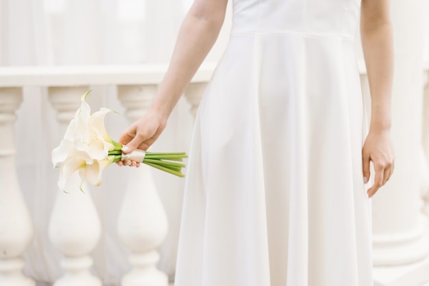 Delicate white bouquet of calla lilies in the hands of the bride at the wedding