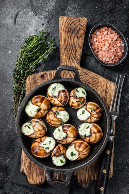 Delicatessen eten Bourgogne Escargots Slakken met kruidenboter in een pan Zwarte achtergrond Bovenaanzicht