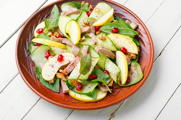 Photo delicious affordable salad of cucumber, spinach, apple and meat tongue.healthy food.spring salad