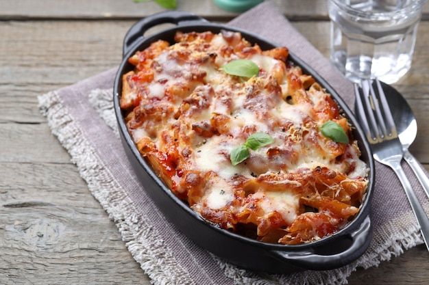 Delicious al forno pasta in baking dish on wooden table closeup