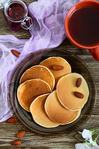 Delicious almond pancakes with tea and jam on a wooden table. Top view.