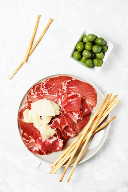 Delicious appetizer with bread sticks and ham, selective focus and top view