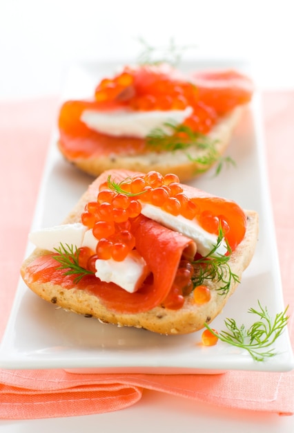 Foto un delizioso aperitivo con caviale rosso salmone e formaggio fresco.