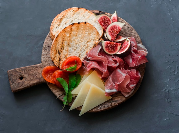 Delicious appetizers for wine or a snack prosciutto figs bread cheese on a rustic wooden cutting board