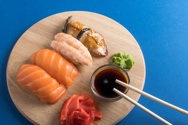 맛있는 간식 초밥 세트가 간장과 젓가락으로 나무 접시에 제공됩니다. 평평하다