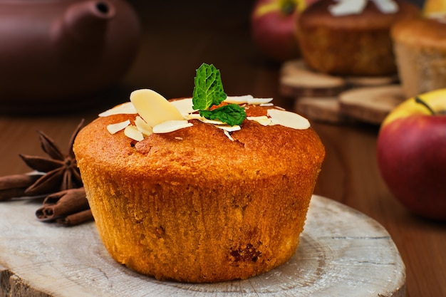Delicious apple muffin with cinnamon with apples and almond flakes decorated with a mint leaf, close-up, selective focus. Tea time or breakfast time, homemade cakes