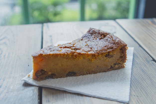 Charlotte deliziosa della torta di mele su un tovagliolo bianco su una tavola in un caffè dalla finestra.