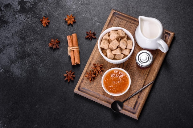 Delicious apricot jam milk and sugar on a wooden cutting board against a dark concrete background