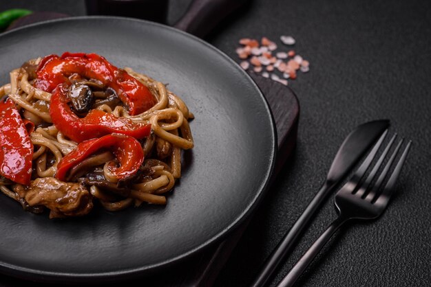 어두운 콘크리트 배경의 세라믹 접시에 야채 버섯 소금과 향신료를 곁들인 맛있는 아시아 우동 요리