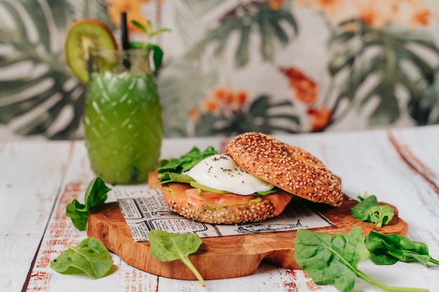 Delicious bagel with sesame and chia bread, inside it contains salmon, fried egg and basil.