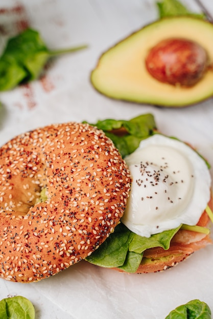 Delizioso bagel con pane al sesamo e chia, al suo interno contiene salmone, uovo fritto e basilico.